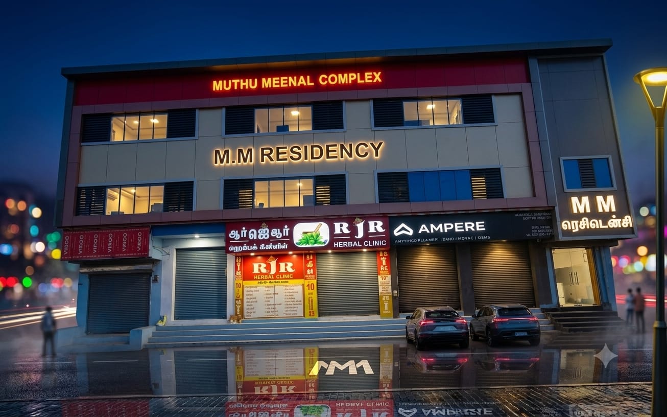 The lit facade of MM Residency on Sekkalai Road, Karaikudi, photographed at dusk after rain